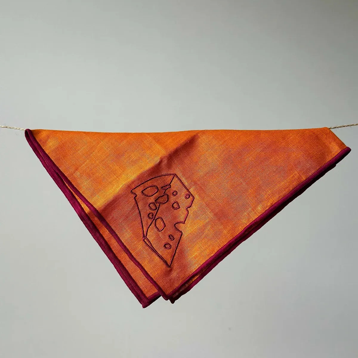 Orange napkin with a cheese slice design on a gray background