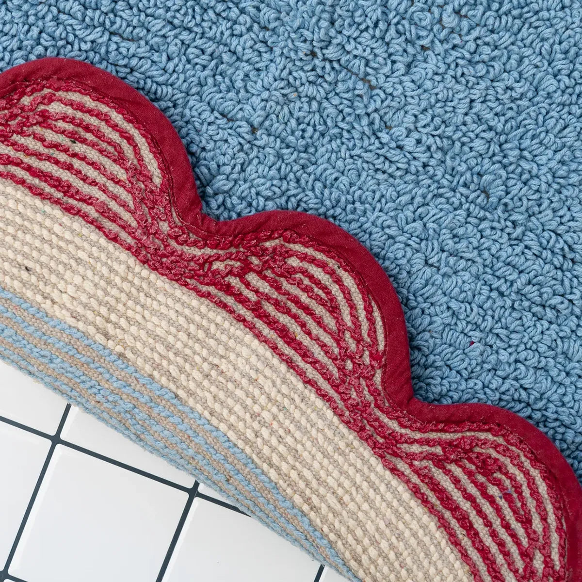 Textured bath mat in blue, red, and beige on a grid background