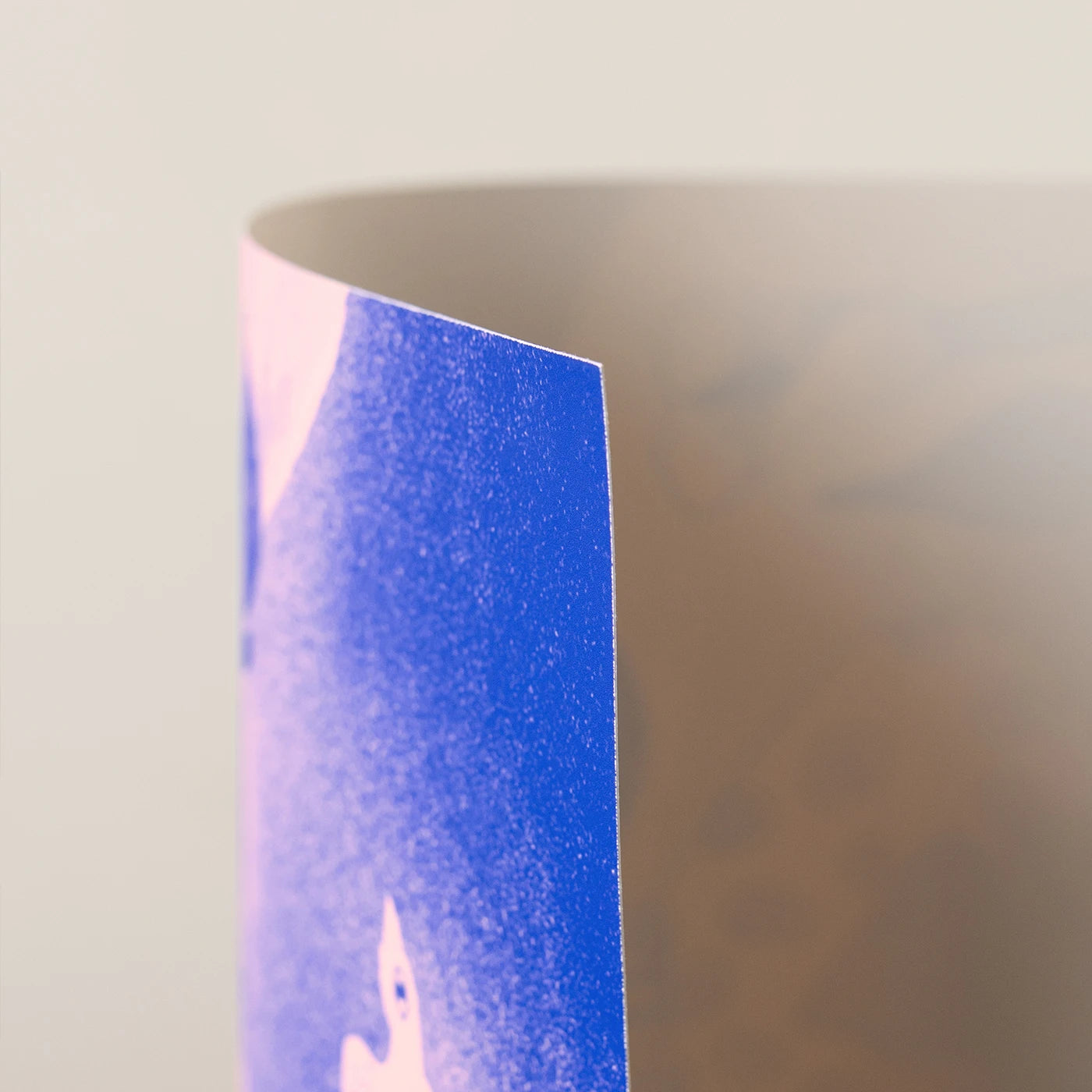 A close-up of an art print showing a blue printed design with a white bird-like graphic against a soft beige background.