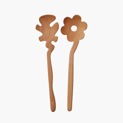 Two light natural wood flower-shaped Serving Friends spoons from Areaware, photographed against a solid off-white background.