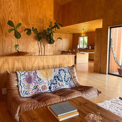 Living room with wooden walls, a brown sofa, and decorative throw blanket elements.