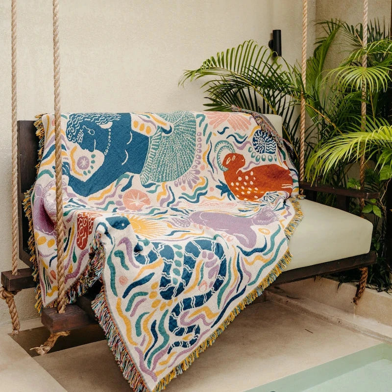 Colorful animal-patterned throw blanket draped over a swing chair with plants in the background