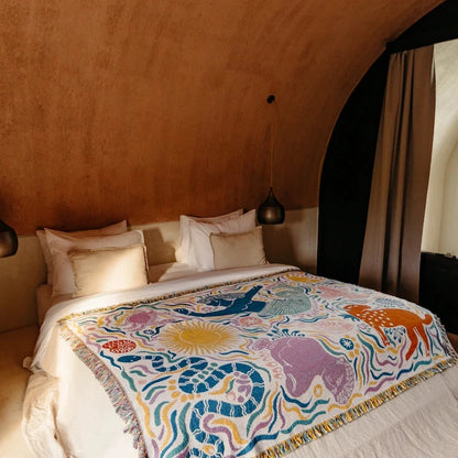 Bed with a colorful blanket featuring mythical greek animals in a bedroom setting.