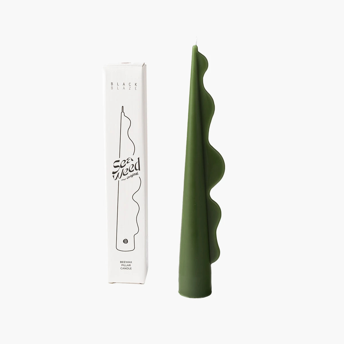 Green candle with wavy design next to its packaging on a white background
