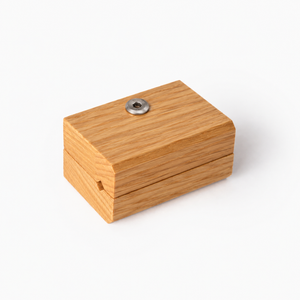 Close up showing one blanket hanger clip in a beautiful oak grain. A round metal screw on top, set against a plain white background.