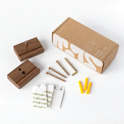 A blanket hanger set of 3 clips in walnut with a  kit laid out on a white background, including 3 screws, 3 wall anchors, 3 white adhesive hooks, an Allen key and a brown packaging box.