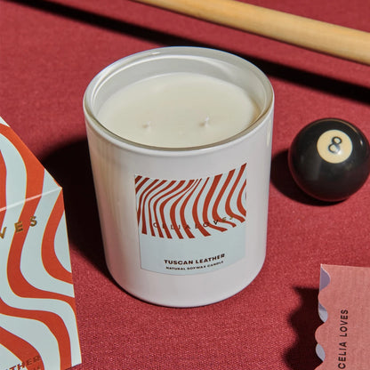 Tuscan Leather candle with striped packaging on a pool table