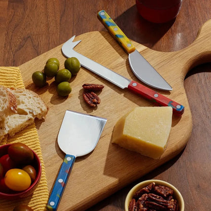 Colorful cheese knives on a cheese board platter