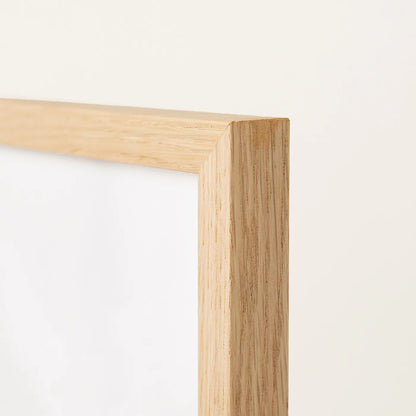 Close-up of a light natural oak wood picture frame corner against a plain off-white background.