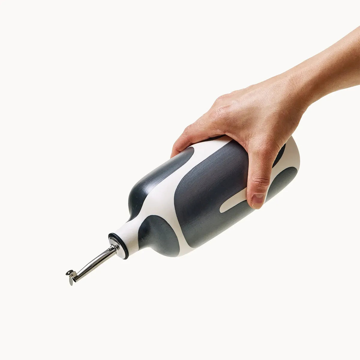 Hand holding a black and white ceramic bottle on a white background