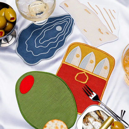 Set of fabric coasters with fish, cheese, olive, and oyster designs on a white surface.