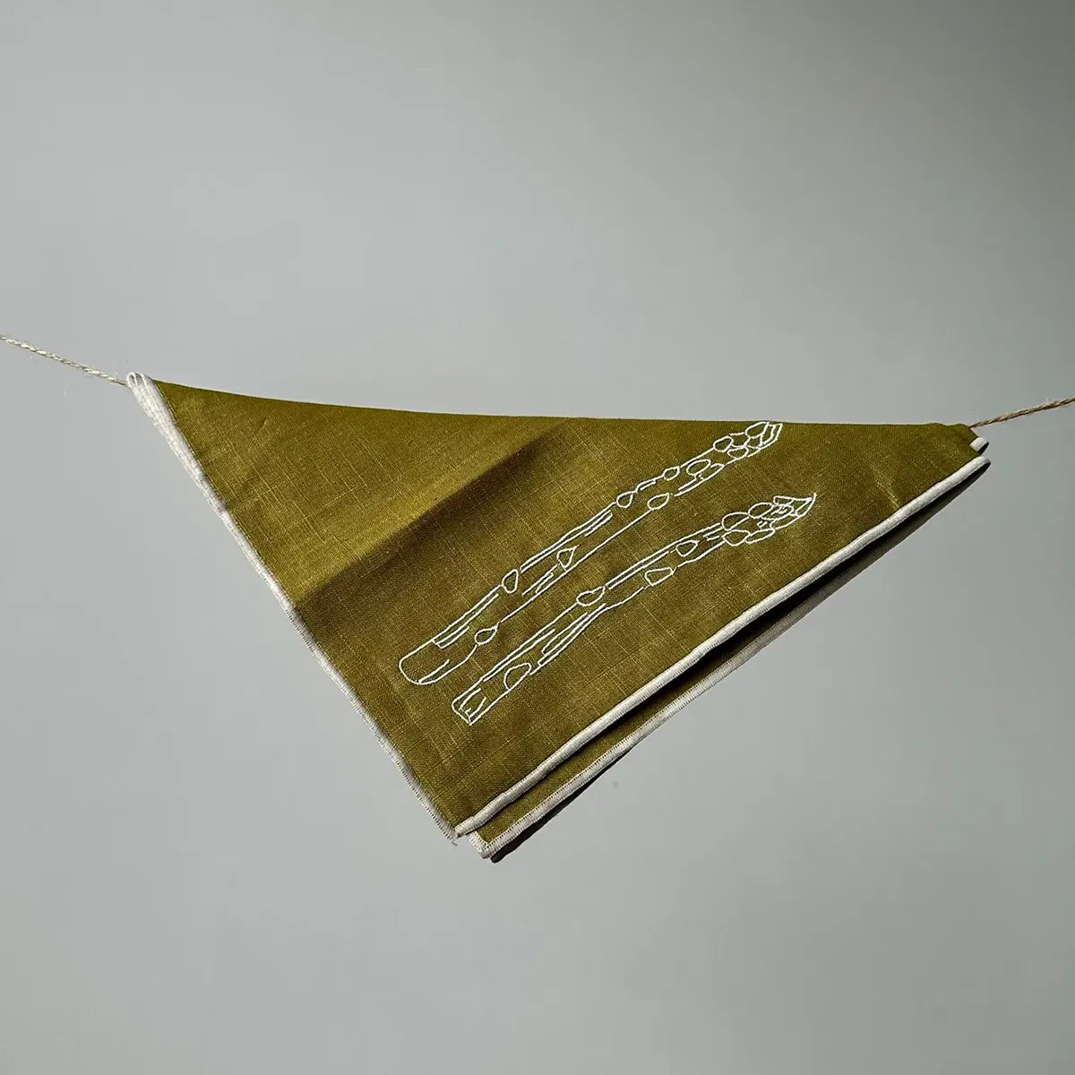 Green fabric napkin with white embroidery on a gray background