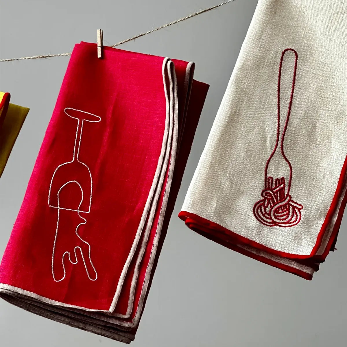 Red and beige napkins with embroidered designs on a gray background