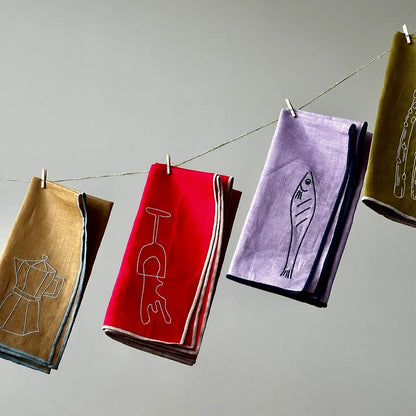 Set of colorful napkins with designs hanging on a line against a gray background
