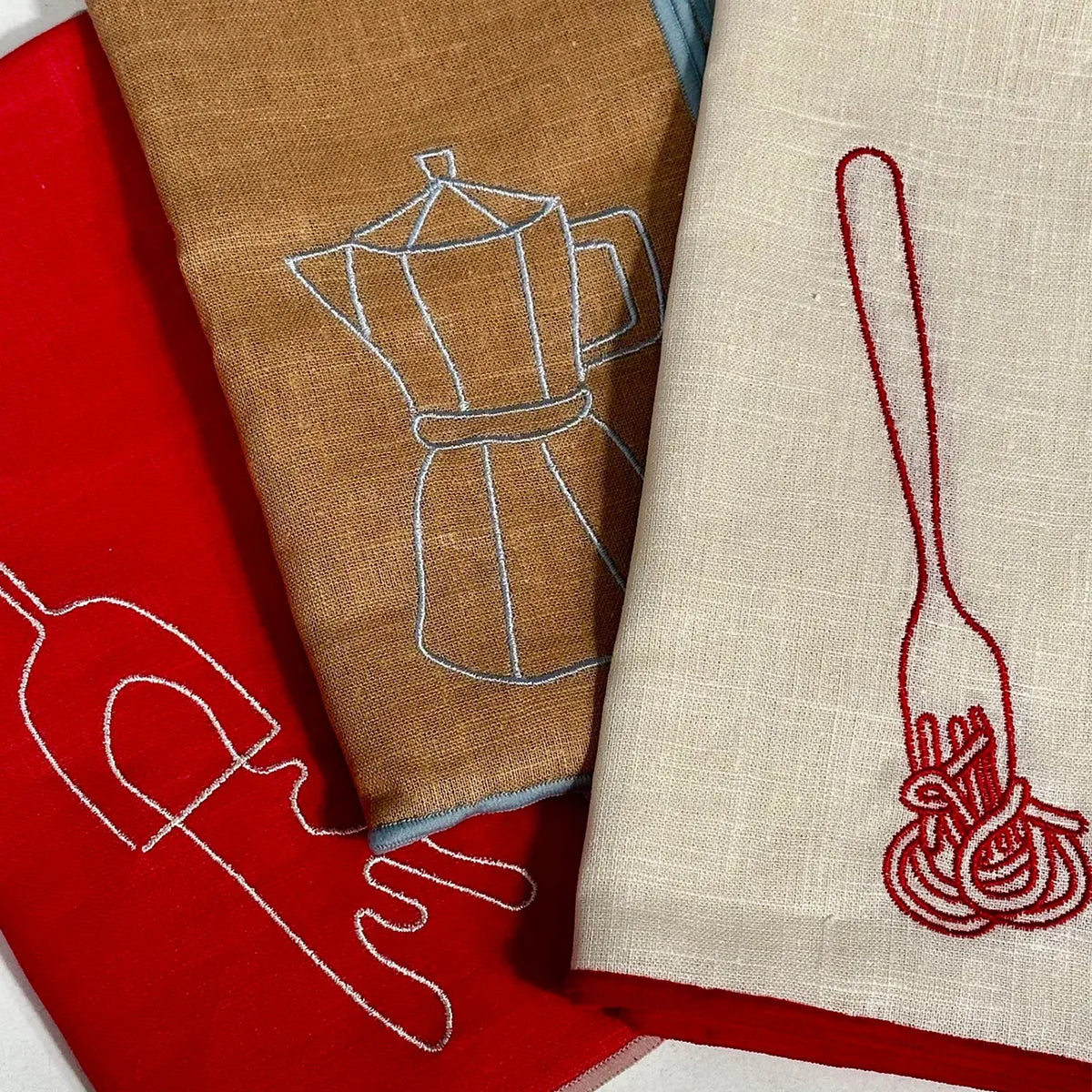 Three embroidered napkins on a flat surface
