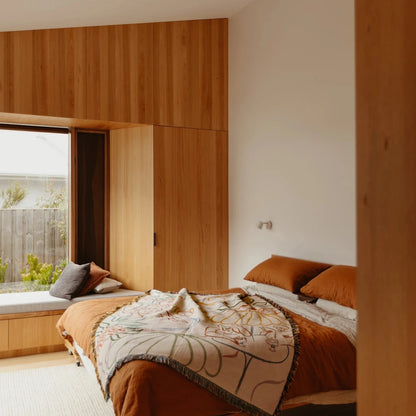 Modern bedroom with wooden walls and a bed with patterned blanket.