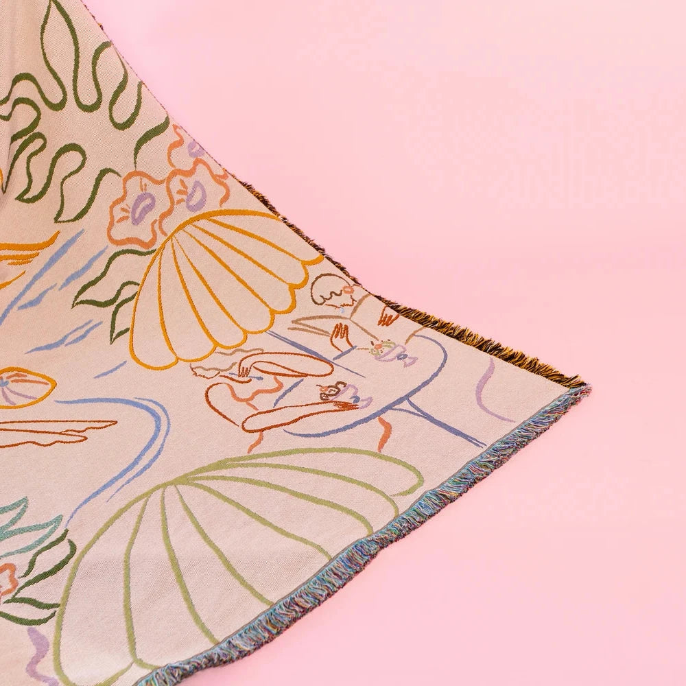 Decorative woven throw blanket with colorful abstract design on a pink background
