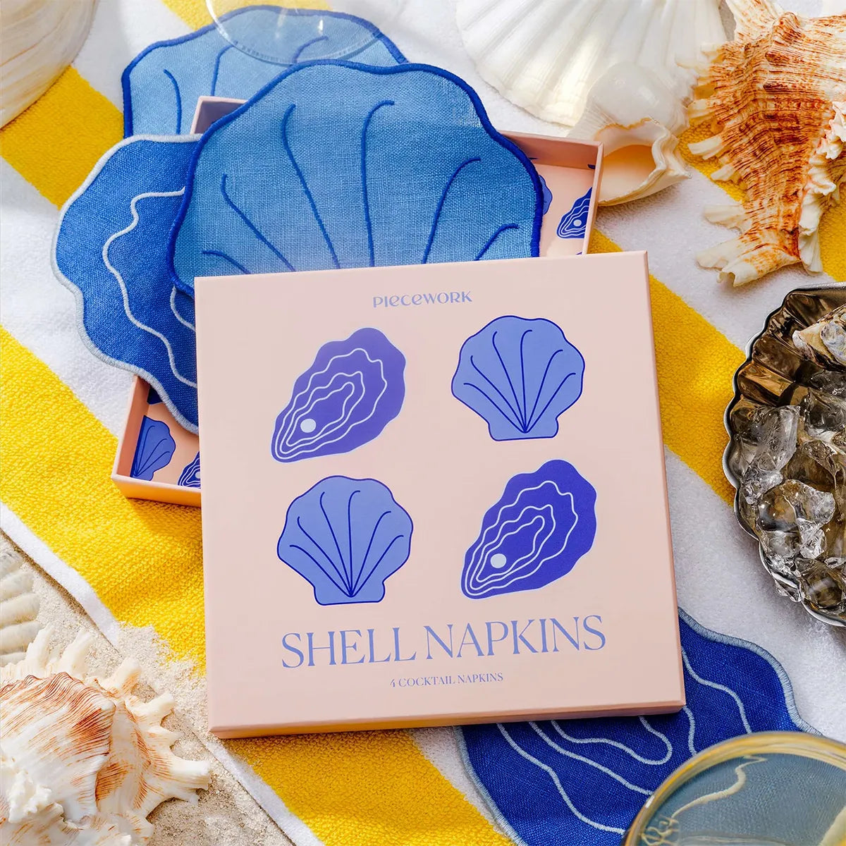 Pack of shell-shaped coasters with a decorative box on a shell-themed surface.