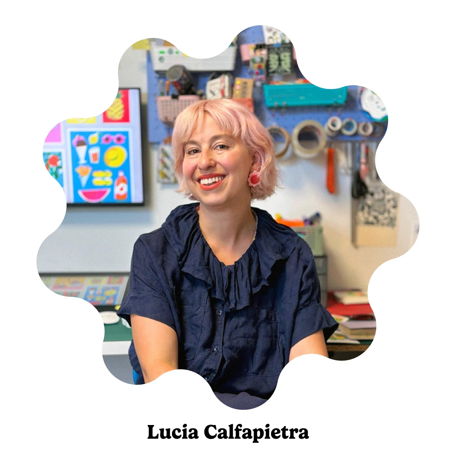 A portrait of a Italian artist Lucia Calfapietra smiling with short pink hair and wearing a dark navy ruffled blouse.