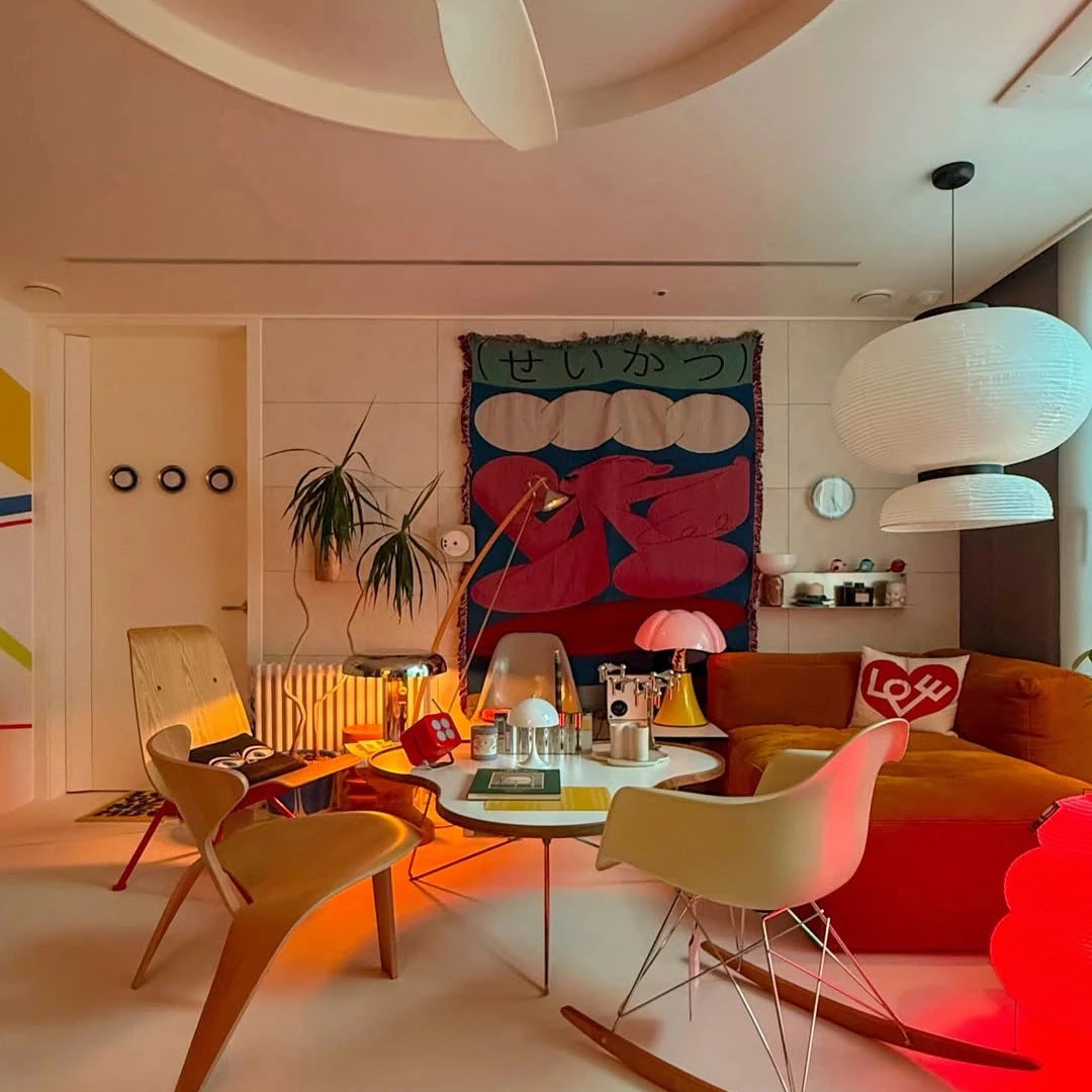 Modern living room with colorful decor, including a large tapestry and unique furniture.